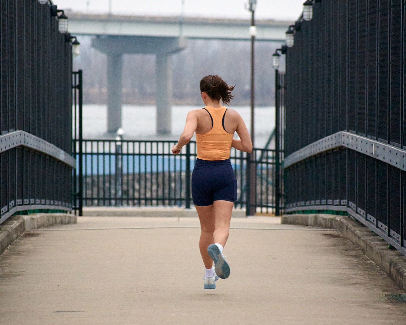 Person running on a bridge with a cityscape in the background