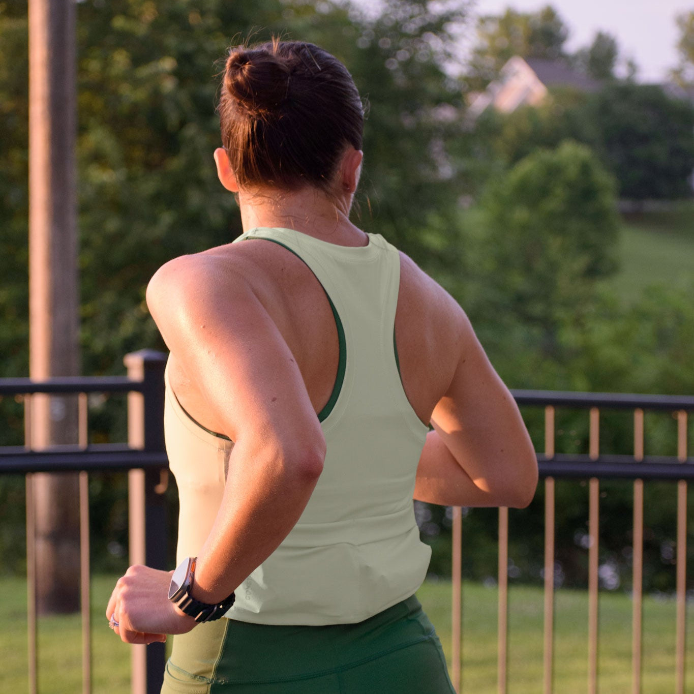 Women wearing a aloe green tank top and evergreen shorts running outdoors.