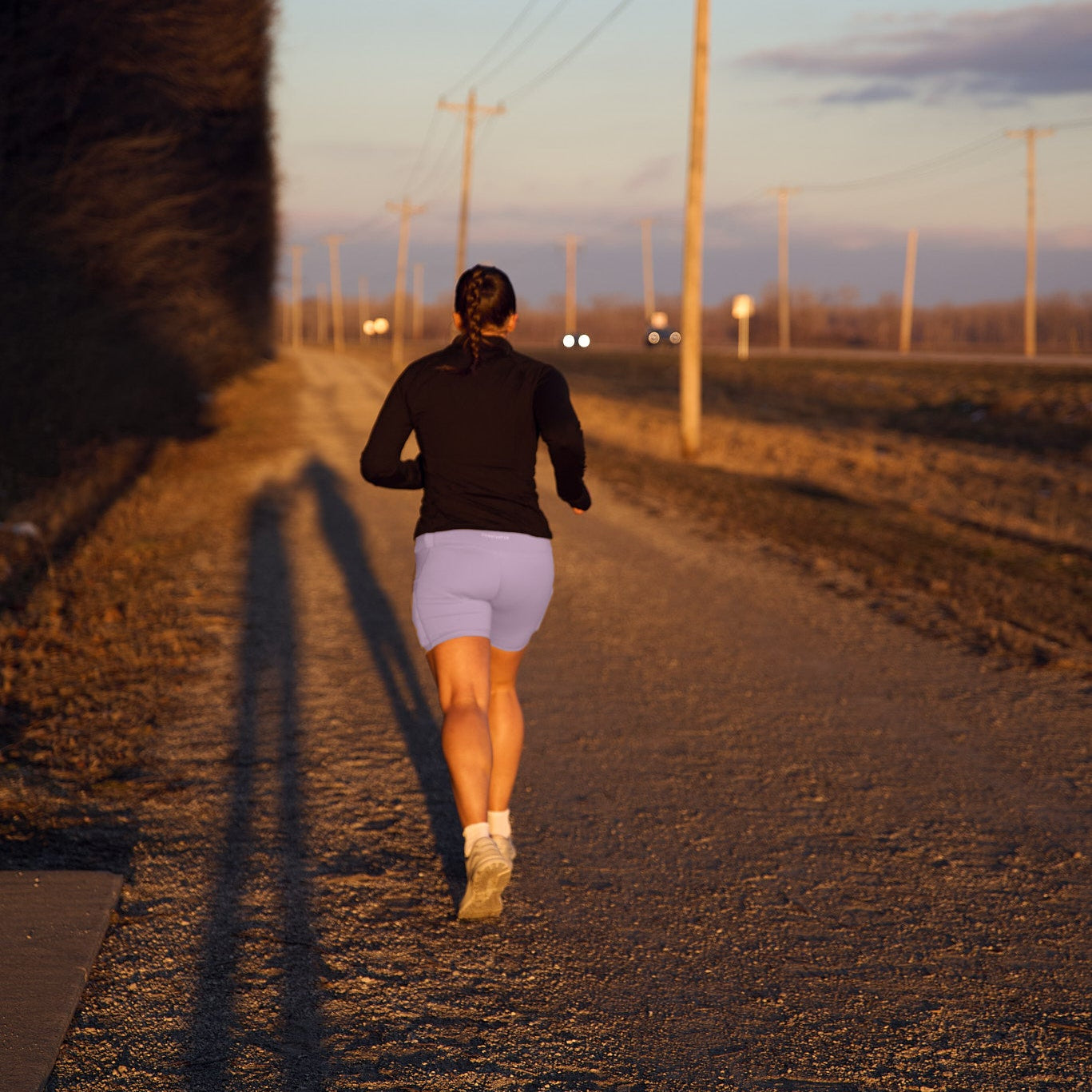 Person running a road with the sunset in the background.
