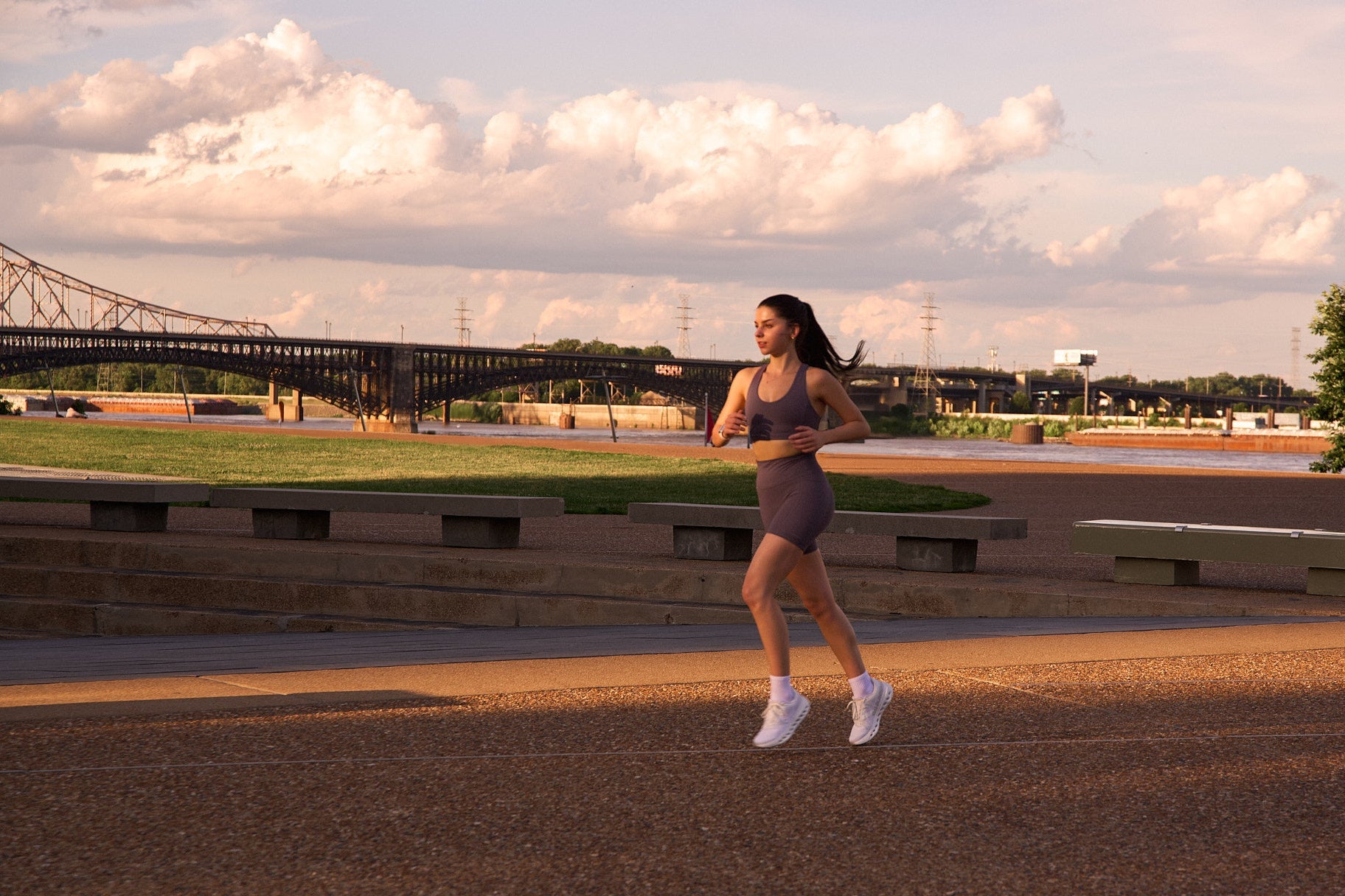 Woman running on a path with a bridge and trees in the background